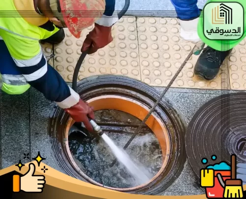 شركة تسليك مجاري في عجمان 0545473541 الدسوقي عامل تنظيف المجاري يستخدم خرطوم ضغط الماء لتنظيف فتحة الصرف الصحي بفعالية.