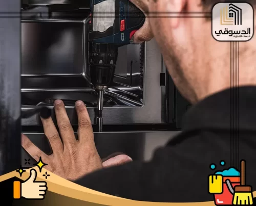 افضل شركة تصليح افران في الفجيرة 0545473541 الدسوقي فني صيانة يفحص الهيكل الداخلي لفرن منزلي باستخدام مفك كهربائي
