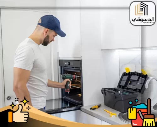 تصليح فرن كهرباء في العين 0545473541 الدسوقي فني صيانة يقف أمام فرن كهربائي مفتوح لفحص الأعطال الداخلية